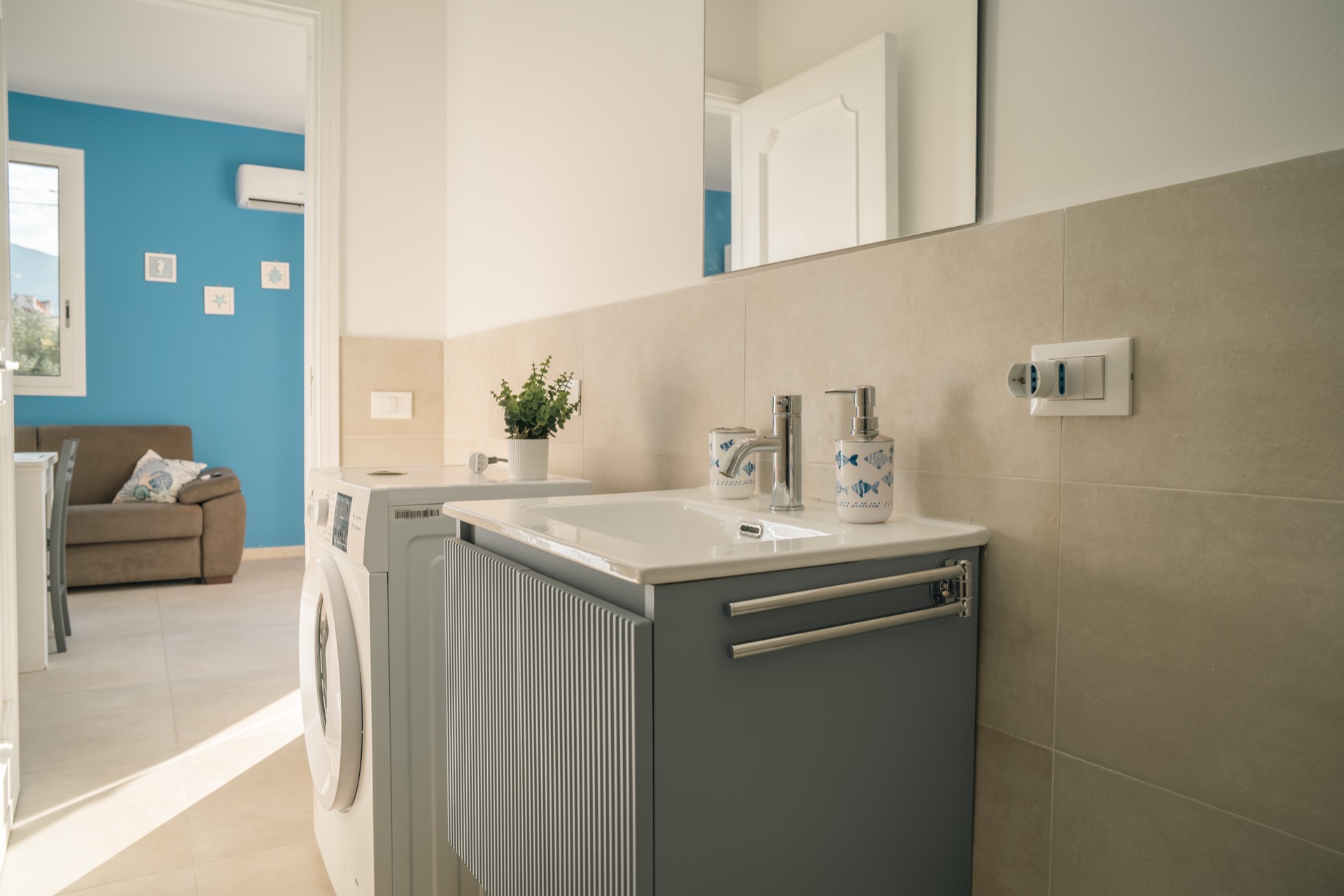 Lavabo e lavatrice del bagno della Dimora Blu con vista sul soggiorno turchese