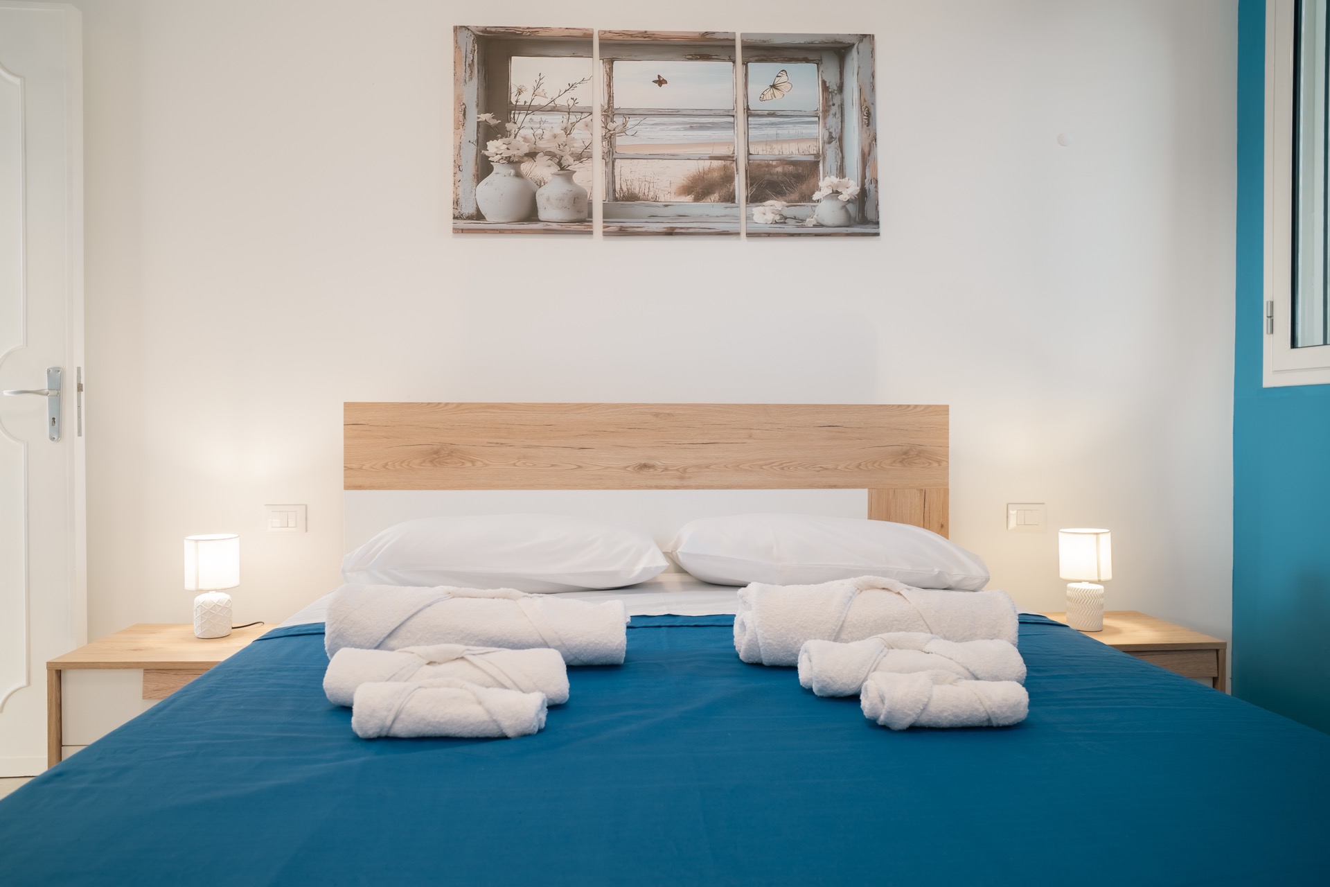 Letto matrimoniale della Dimora Blu con asciugamani arrotolati e testata in legno