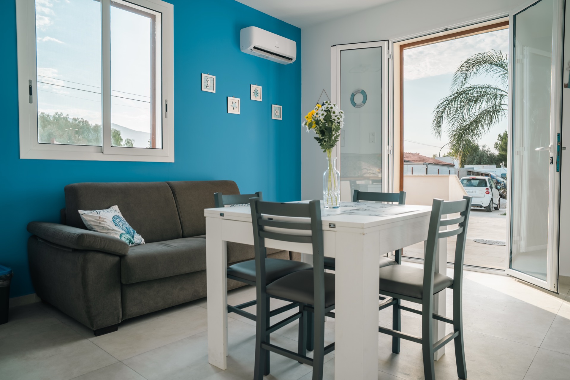 Zona divano e tavolo da pranzo della Dimora Blu con porta aperta sul terrazzo